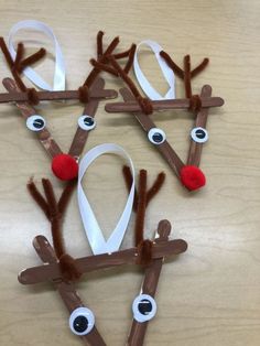 paper plate reindeers made out of sticks and white ribbon with red noses on them