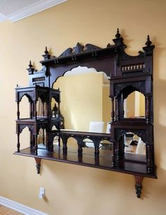 an ornate wooden mirror hanging on the wall next to a shelf with mirrors in it