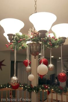 a chandelier with christmas decorations hanging from it's sides and lights on the ceiling