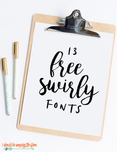 a clipboard with the words free swirly font on it next to two pens