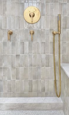 the shower head is gold in color, and it's tiled walls are white