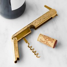 a bottle opener and corkscrew on a marble countertop next to a vase