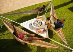 four people sitting in hammock with food and drinks on the table, overhead view