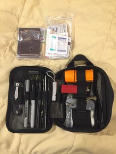 the contents of an emergency kit are neatly packed in a black case on a bed