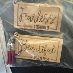 two wooden key chains with the words fearless and month 11 printed on them in black ink