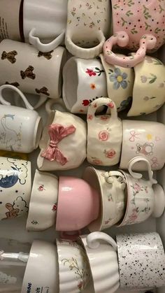 there are many cups and saucers in the box together, all decorated with different designs