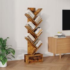 a tall wooden book shelf sitting on top of a hard wood floor next to a potted plant