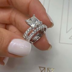 a woman's hand holding a diamond ring with two diamonds on top of it