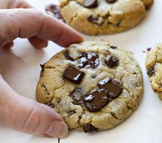 a person picking up a chocolate chip cookie