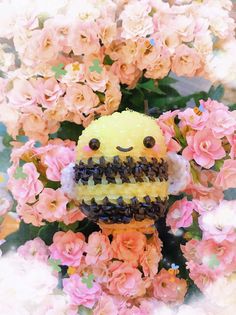 there is a small yellow stuffed animal surrounded by pink flowers