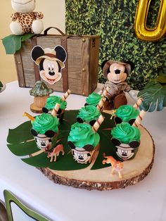 mickey mouse cupcakes with green frosting on a tree slice at a birthday party