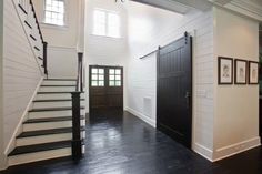 an empty room with stairs and pictures on the wall next to the door that leads up to the second floor