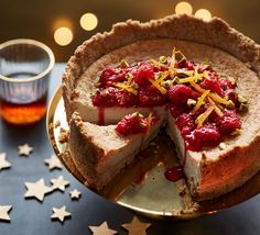 a cheesecake with raspberry sauce and pistachio topping on a gold plate