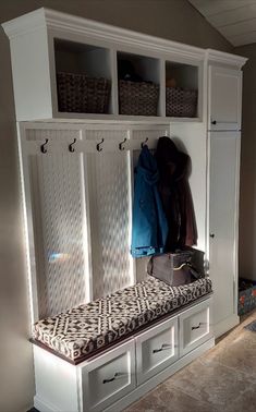 a white bench with two coats hanging on it's sides and some drawers underneath