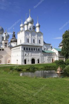 an old white church in the middle of a field with water and trees around it