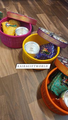 three colorful containers filled with food sitting on top of a wooden floor next to each other