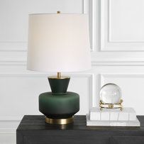 a green lamp sitting on top of a table next to a night stand with a marble base