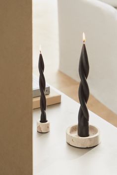 two candles sitting on top of a white table