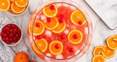 oranges, cherries and ice in a bowl on a marble table with other fruit