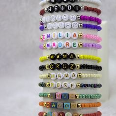 a stack of bracelets with words written in different languages and letters on each bead