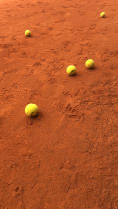 four tennis balls are laying on the ground