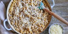 a pan filled with pasta and cheese on top of a wooden table