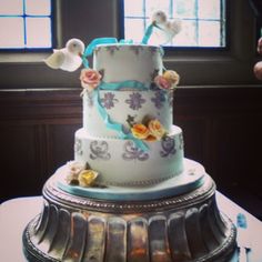 a three tiered cake sitting on top of a table in front of a window