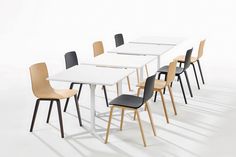 a white table with six black chairs and one light brown chair in front of it