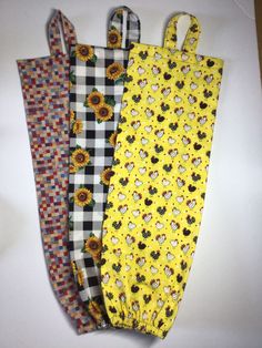 four sunflowers and checkered fabric bags are lined up on a white surface