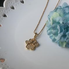 a gold plated necklace with a flower on it and a blue hydrant in the background