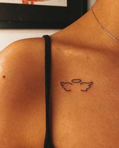 the back of a woman's shoulder with a small tattoo on her left side