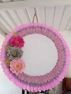 a paper plate with flowers on it hanging from the ceiling in front of a mirror