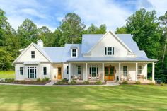 a large white house sitting in the middle of a lush green field with lots of trees