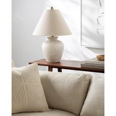 a white lamp sitting on top of a table next to a couch in a living room