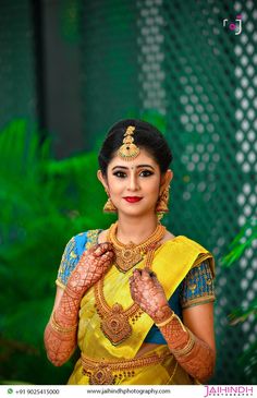 a woman in yellow and blue sari holding her hands up to her chest, with green