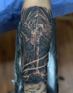 a man's arm with an angel on it and a cross in the middle