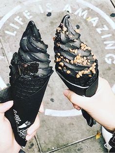 two ice cream cones with sprinkles on them are being held by someone's hands