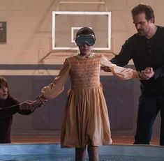 a man and two children wearing blindfolds standing in front of a pool with water