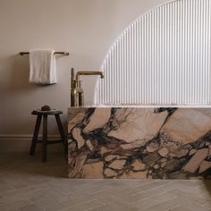 a marble bathtub in a bathroom next to a stool