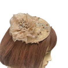 "An antique gold fascinator is covered with intricate beaded gold lace. A champagne colored handmade beaded flower sits on one end and this small elegant hat or gold fascinator is perfect for a formal event. This versatile piece can be worn in many ways. If you choose to have it mounted on a headband it will be fixed on the headband and will be able to be worn on either side of your head. The golden mini hat attaches to your hair with an alligator clip attached to the underside or a satin wrappe Handmade Gold Hat For Kentucky Derby, Elegant Bead Cap Headband, Elegant Wedding Hats And Headpieces With Handmade Flowers, Gold Gatsby Style Formal Headpieces, Elegant Headpiece With Handmade Flowers And Pinched Crown, Vintage Gold Headpiece For Evening, Elegant Cream Fascinator For Vintage Events, Elegant Handmade Headpiece With Structured Crown, Elegant Vintage Hat Headpieces