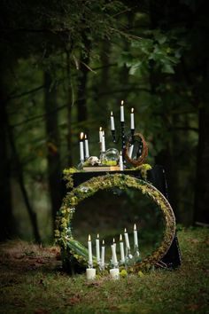 a table topped with candles in the middle of a forest