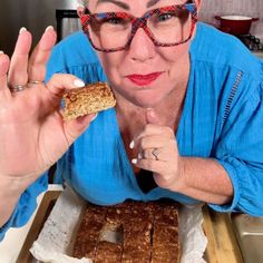 an older woman with glasses is holding up a piece of food in front of her face