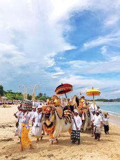 some people are standing on the beach with animal masks and umbrellas in hand while others walk by