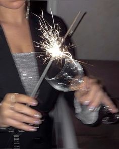 a woman holding a wine glass with a sparkler in it