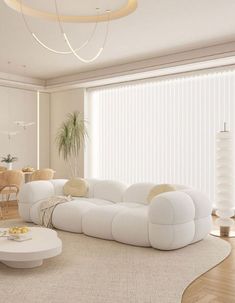 a large white couch sitting in a living room next to a coffee table and chairs