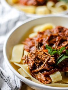 a white bowl filled with pasta and meat