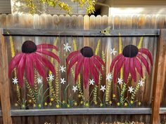 a fence with flowers painted on it in front of a wooden fence and some grass