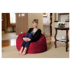 a woman sitting on top of a red bean bag chair