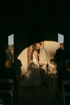 a bride and groom kissing in front of an arch at the end of their wedding ceremony