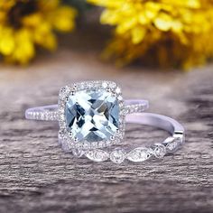 an engagement ring with a blue topazte surrounded by white diamonds on a wooden surface